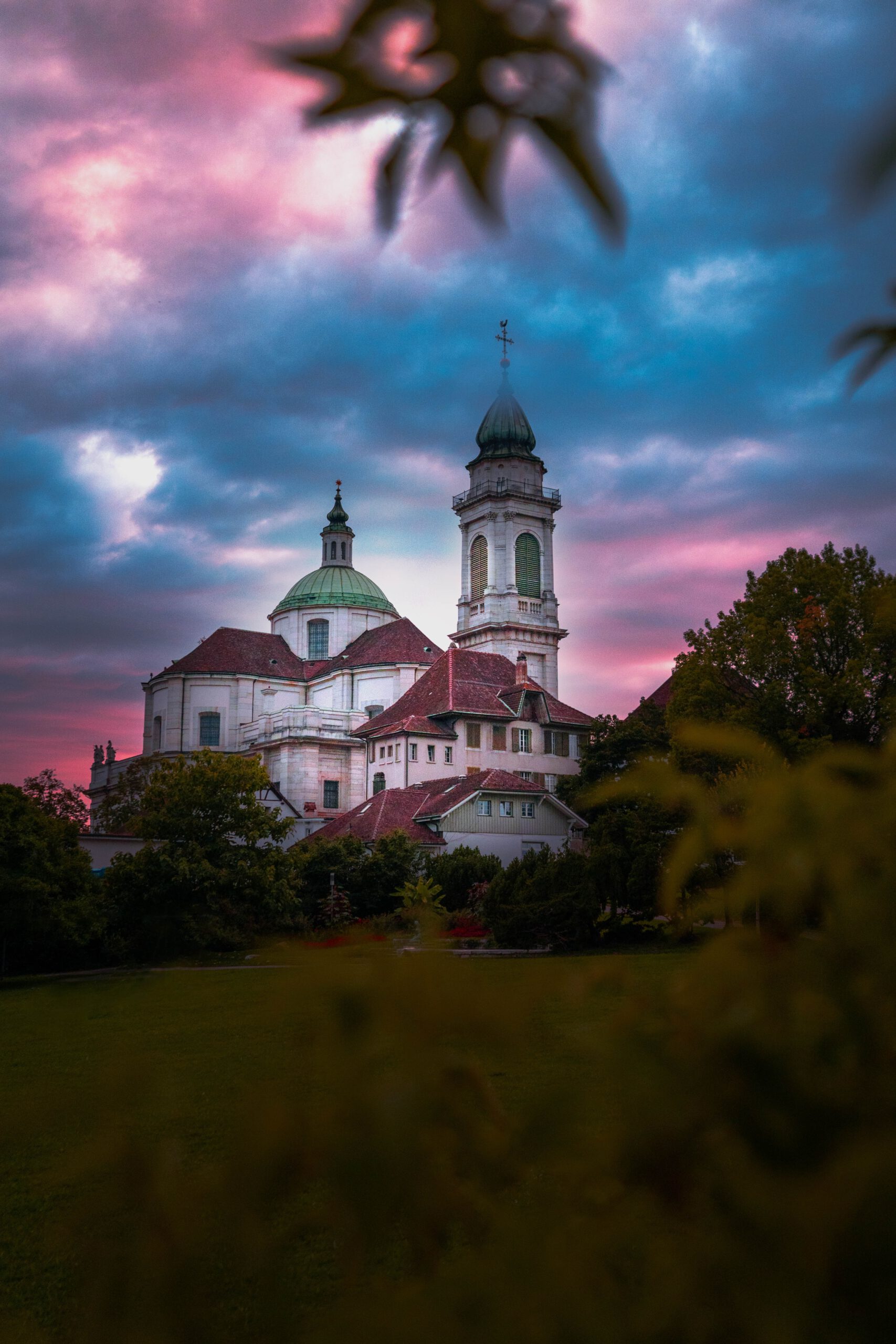 Grosse Kirche mit Wiese davor und aufziehenden dunklen Wolken