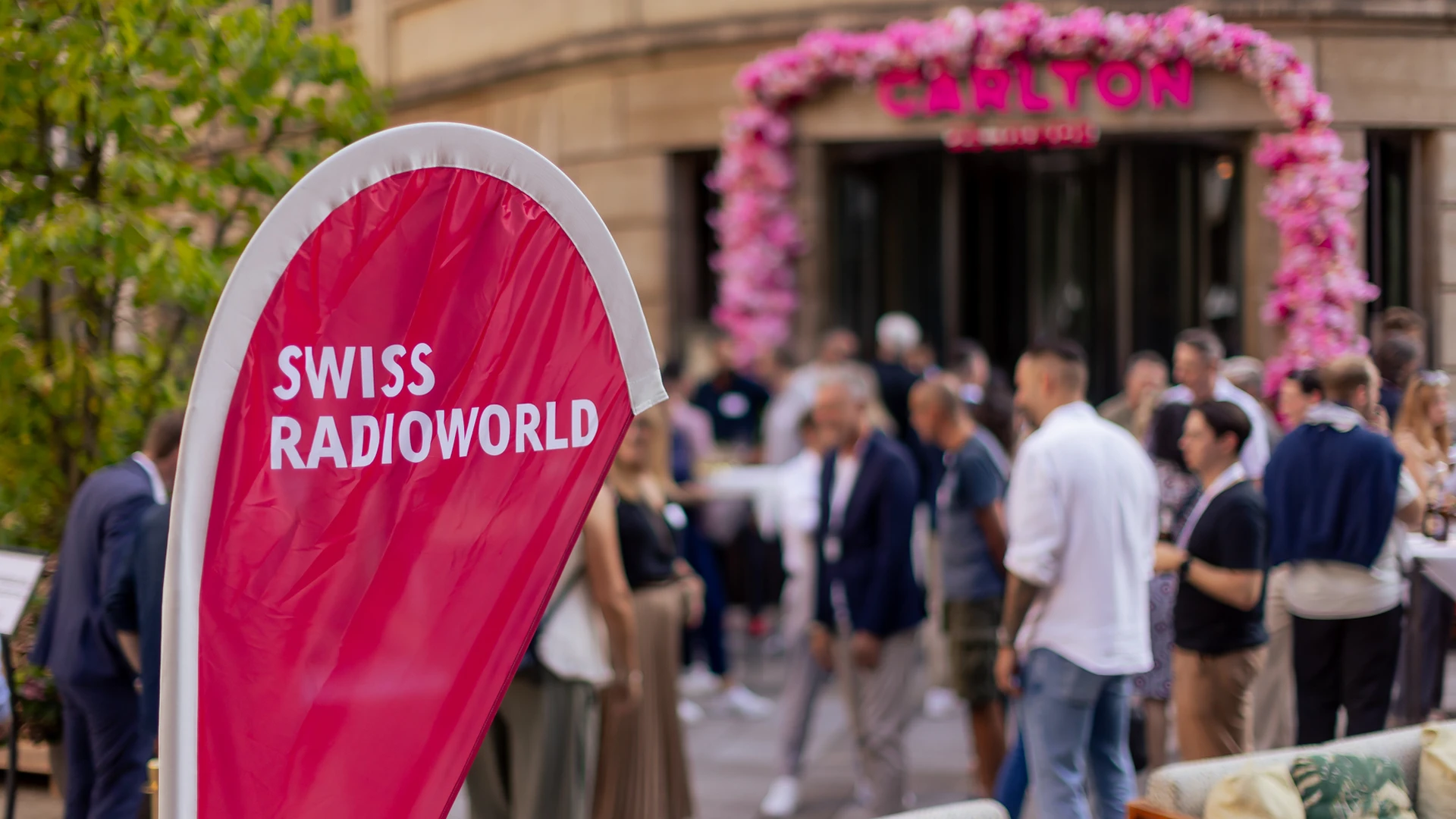 Radio Night Swiss Radioworld Logo im Vordergrund, Party im Hintergrund