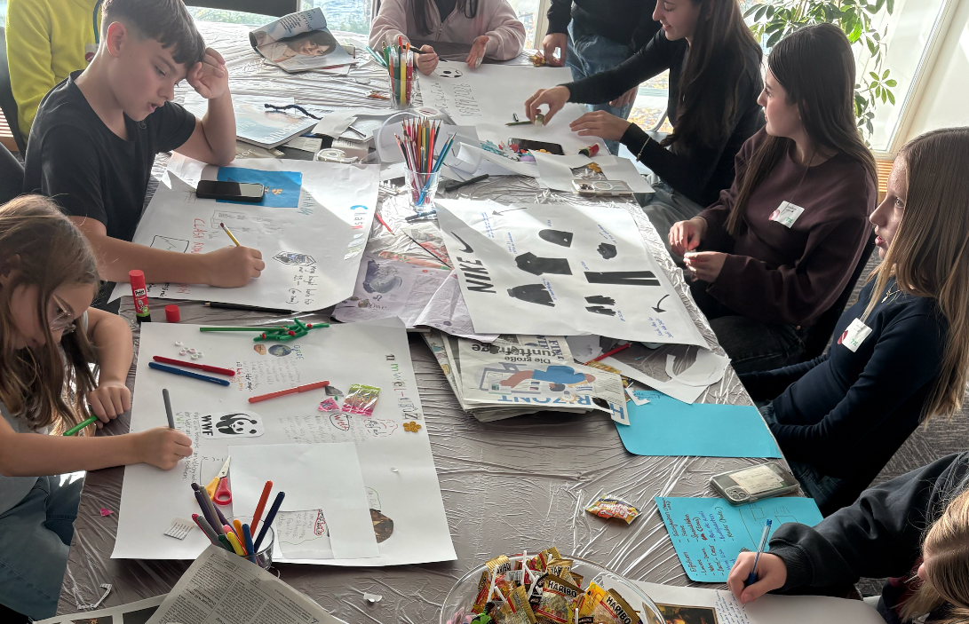 Kinder sitzen um einen Tisch malen und basteln.