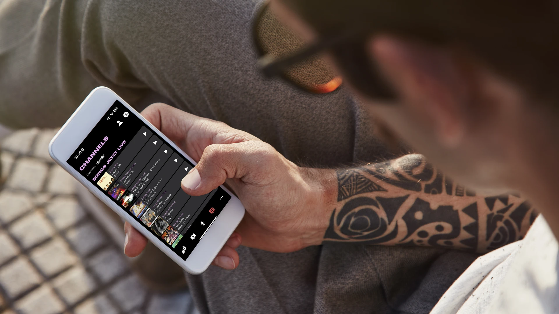 Man sits with cell phone and looks at audio platform